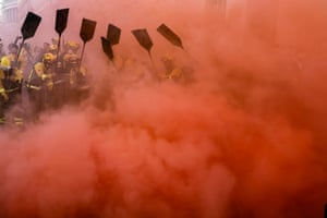 Red smoke engulfs firefighters during a demonstration