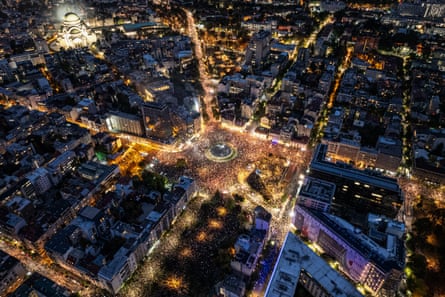 Aerial night view of a huge crowd filling a Belgrade square during a rally, surrounded by illuminated streets