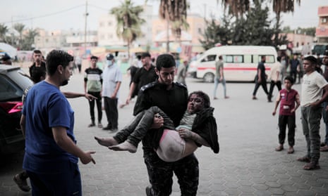 A man carries a wounded child towards the Al-Aqsa Martyrs Hospital in the city of Deir Al-Balah.