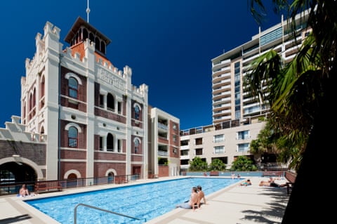 Bathers sit by a large rectangular pool behind a series of buildings in the Moore Park Gardens.