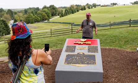 People pose for pictures at the plaque marking the Woodstock music festival in Bethel, New York.