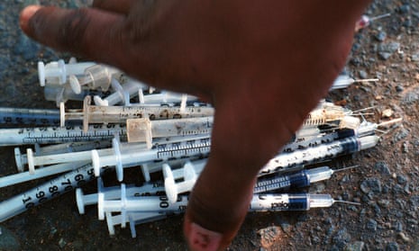 A heroin addict reaches for a pile of used syringes before trading them in for clean ones in San Juan, Puerto Rico, Nov. 3, 2000. 
