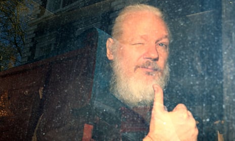 Assange, now with a white beard, winks and gives a thumbs up to reporters