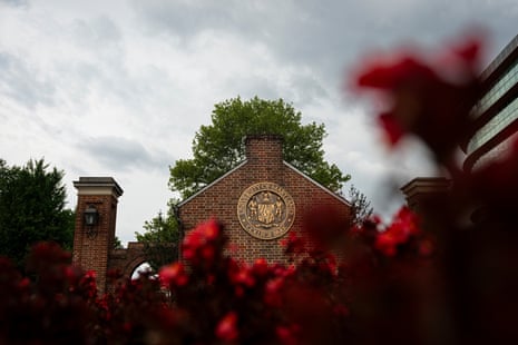 University of Maryland's brick entrance bears its seal, framed by a tree and red flowers