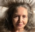 A woman with gray hair reclines on a pillow or sofa.
