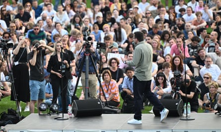 Ilya Yashin stands on a stage and is photographed from behind as he addresses a large crowd of people, many taking photographs or filming him
