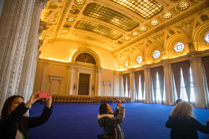 Tourists take pictures inside ‘Unirii’ hall, the largest room inside the Romanian parliament building in Bucharest