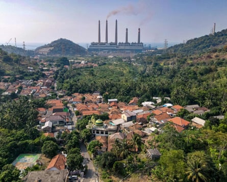 A view from across the rooftops of a village to a coal power plant