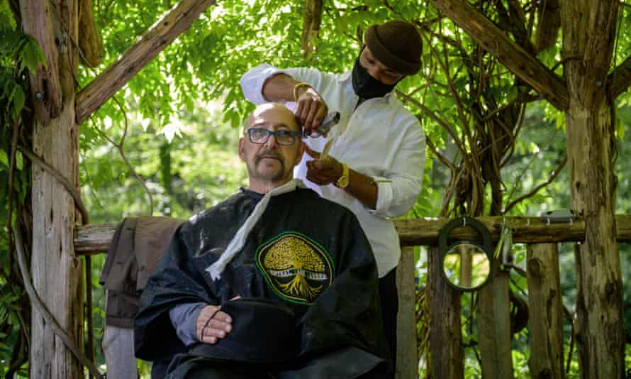 Barber Herman James cuts a clients hair under a pergola in Central Park in New York City.