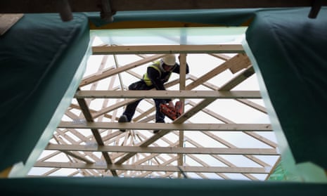 A builder uses a nail gun on roof timbers at a Persimmon construction site