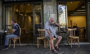 People sit outside of a coffee shop in Athens, Greece.