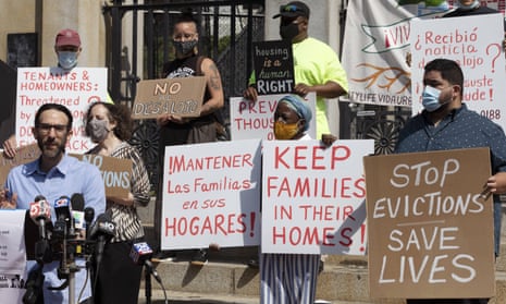 People from a coalition of housing justice groups hold signs protesting evictions in Boston.