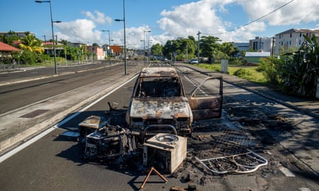 A burned car and debris block a road after unrest triggered by COVID-19 curbs, which has already rocked the nearby island of Guadeloupe, in Fort-de-France, Martinique.