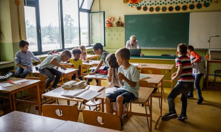 Happy students making chaos during a class at elementary school while teacher is ignoring them.