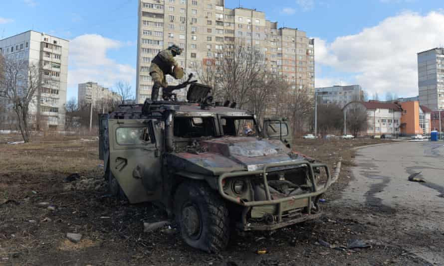 A Ukrainian Territorial Defence fighter examines a destroyed Russian infantry mobility vehicle Gaz Tigr after an attack in Kharkiv, 27 February