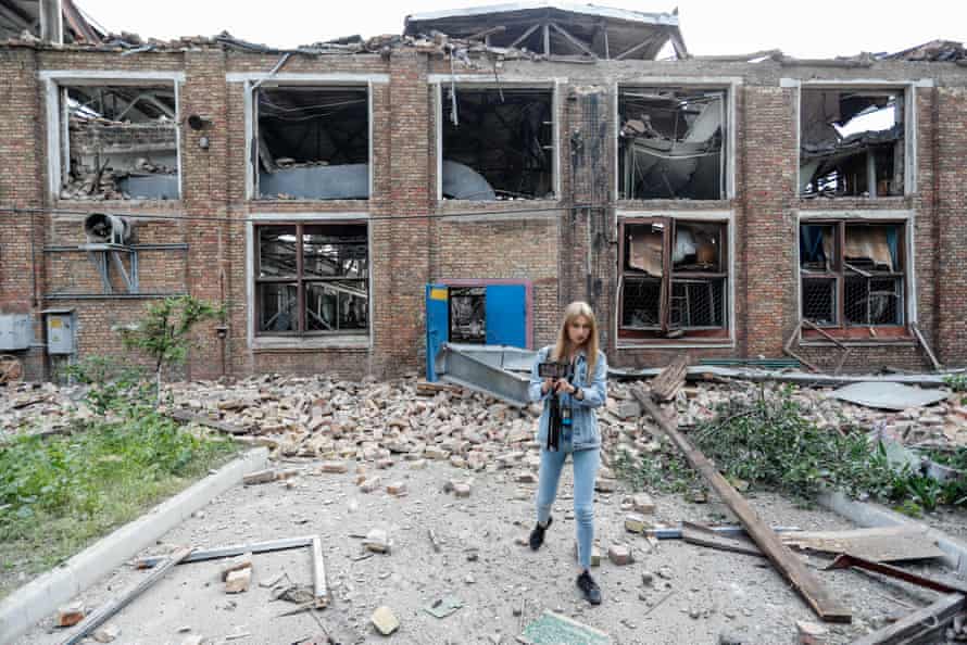 A woman is seen in front of a damaged building at a railway repair plant in Kyiv.