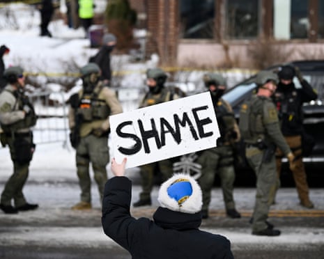 A protester holds a sign reading 'Shame' at federal law enforcement in Minneapolis