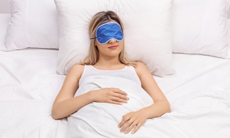 Young woman sleeping on a comfortable bed with blue eye mask
