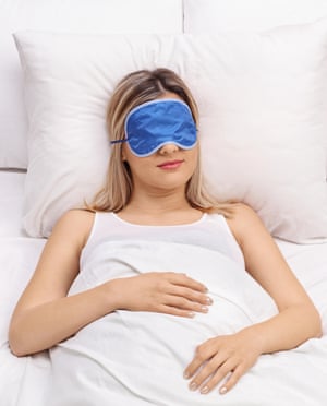 Young woman sleeping on a comfortable bed with blue eye mask