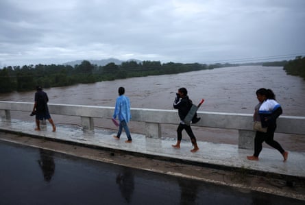 People cross a bridge over a swollen river as Hurricane Simon approaches MexicoâÂÂs Pacific coast in Costalegre, Jalisco state.