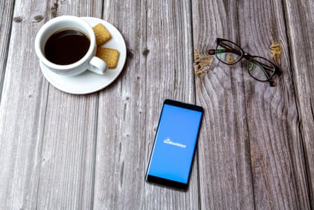 A mobile phone laid on a wooden table with the Loveholidays app open next to a coffee