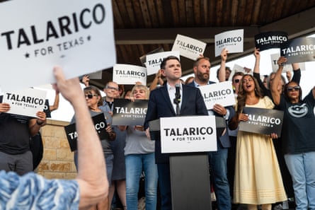 People hold signs that read ‘Talarico for Texas’ as a man in a suit looks out.