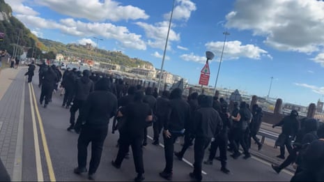Dozens of masked men walking along a road near the port.