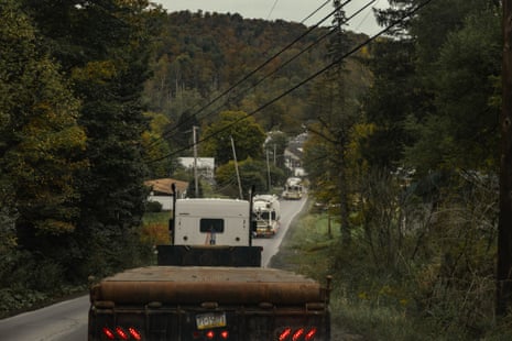 Trailers driving along a street surrounded by trees