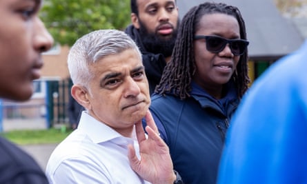Sadiq Khan looks off camera with his hand raised to his face