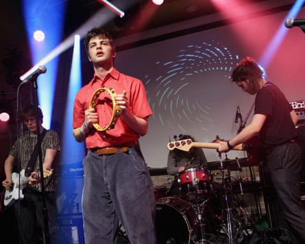 The band on stage, with Grian Chatten at the front holding a tambourine