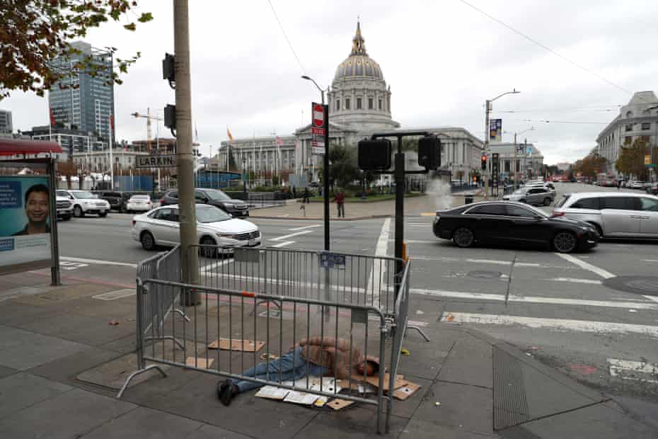 A homeless man sleeps on the sidewalk across from San Francisco’s city hall. 