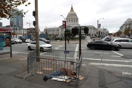 A homeless man sleeps on the sidewalk across from San Francisco’s city hall. 