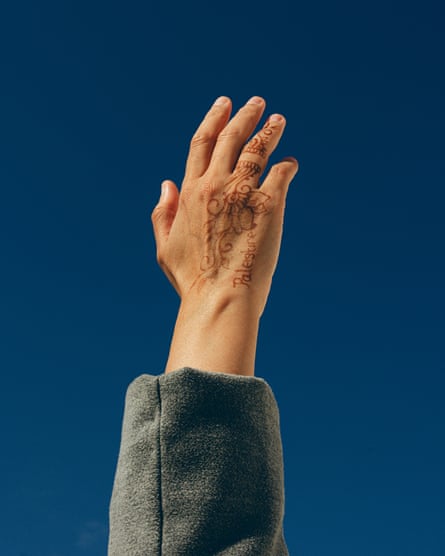 a woman’s hand covered in henna with the words Palestine reaches for the sky