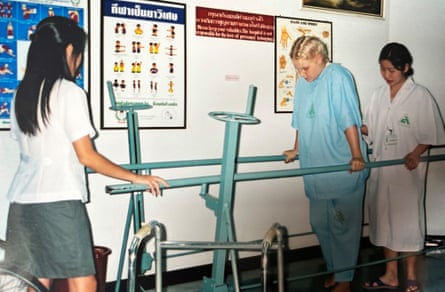 Jones trying to walk with the aid of parallel bars, watched by medical staff