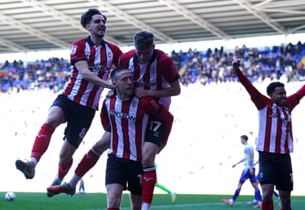 Lincoln players leap on Jack Moylan after his 96th-minute winner against Reading.