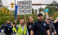 A group of people walk together, holding signs like 'Strike strike strike'