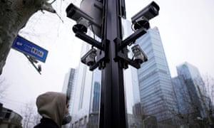 A man wearing a protective face mask walks under surveillance cameras in Shanghai