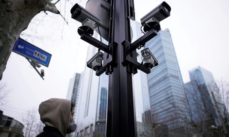 A man wearing a face mask walks under surveillance cameras