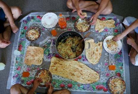 Four Hazara asylum seekers sit down to a meal of qabuli palaw with fresh Afghan bread