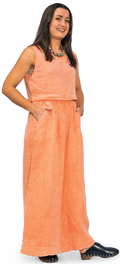 A smiling woman with straight dark hair in a light orange sleeveless top and trousers.