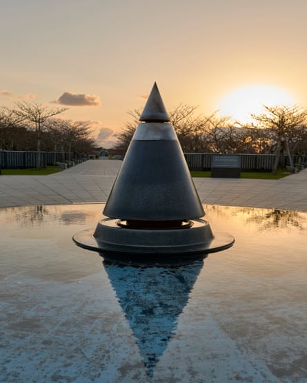 The Cornerstone of Peace memorial, a conical structure, in a cenotaph setting with the sun on the horizon over bushes in the background