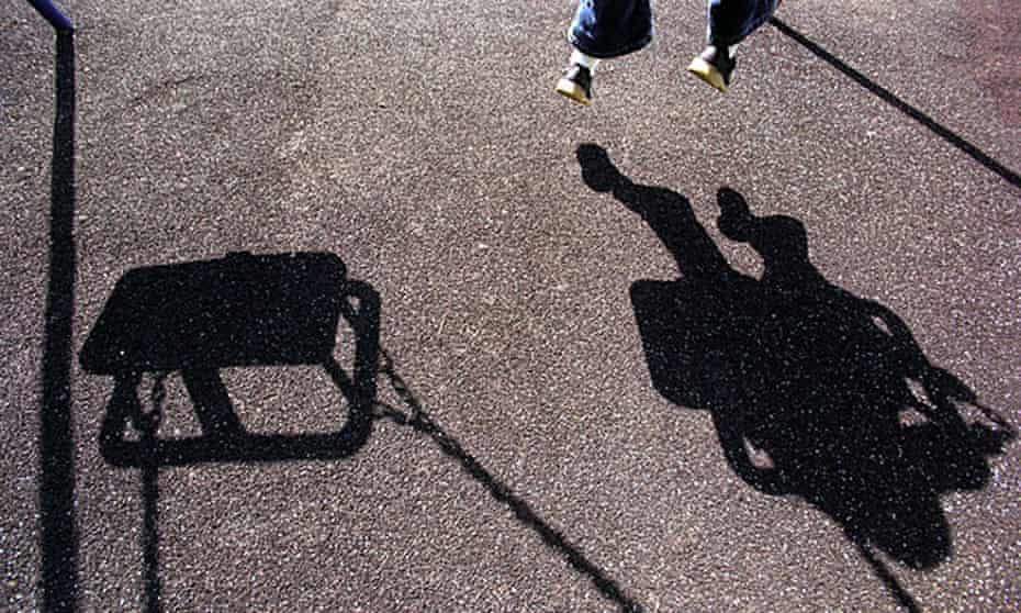 The shadow of a young girl or boy playing on a swing