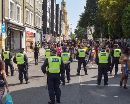 A line of police officers in the street in front of a large crowd of revellers at Notting Hill carnival