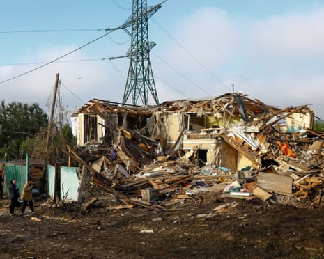 A police officer and residents stand in front of a private building which was heavily damaged during a Russian missile strike in the town of Vyshhorod, Ukraine.