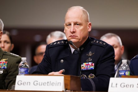 man in military uniform sits before microphone