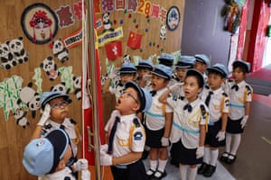 Nursery children in uniform salute a flag