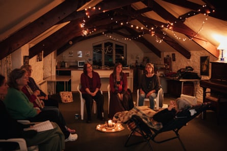 Members of the MoorHeart threshold choir near Totnes, Devon, UK, in a dimly lit room with candles and string lights