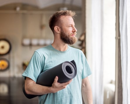 A person holding with exercise mat looking out of window