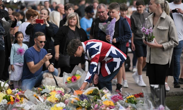 A mourner lays a bouquet of flowers outside Buckingham Palace on Saturday.