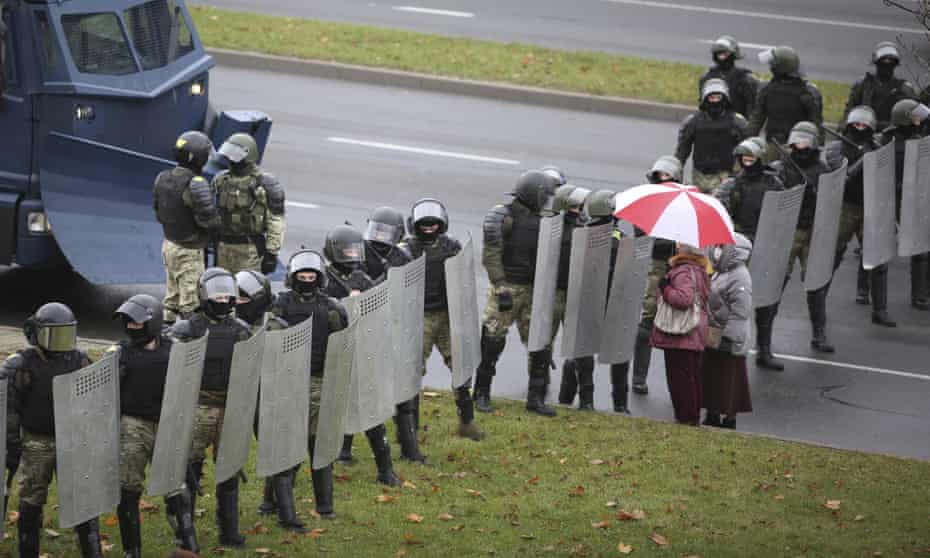 Two people face a line of riot police during a protest in Minsk